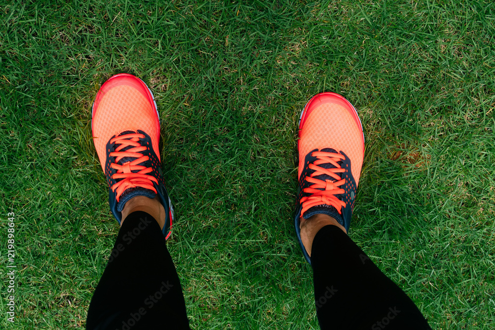 Running shoes of woman athlete runner on grass. Female jogger