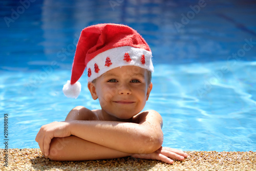 Boy in pool with santa hat. Concept: christmas holiday in hot country