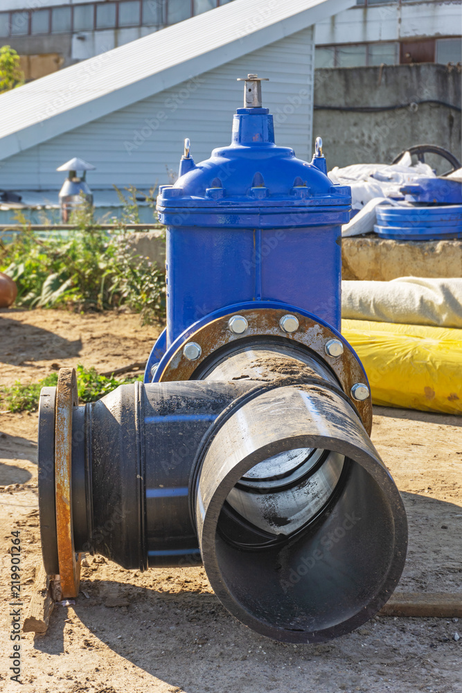Elements of the pipeline, plastic pipes, cast iron valve at a construction site Elements of the pipeline, plastic pipes, cast iron valve at a construction site