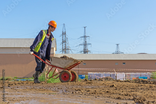 Worker is carrying the soil on the wheelbarrow