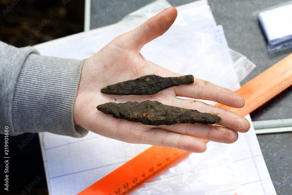 Archeology: rusty arrowheads of medieval arrows lie on the hand of a scientist