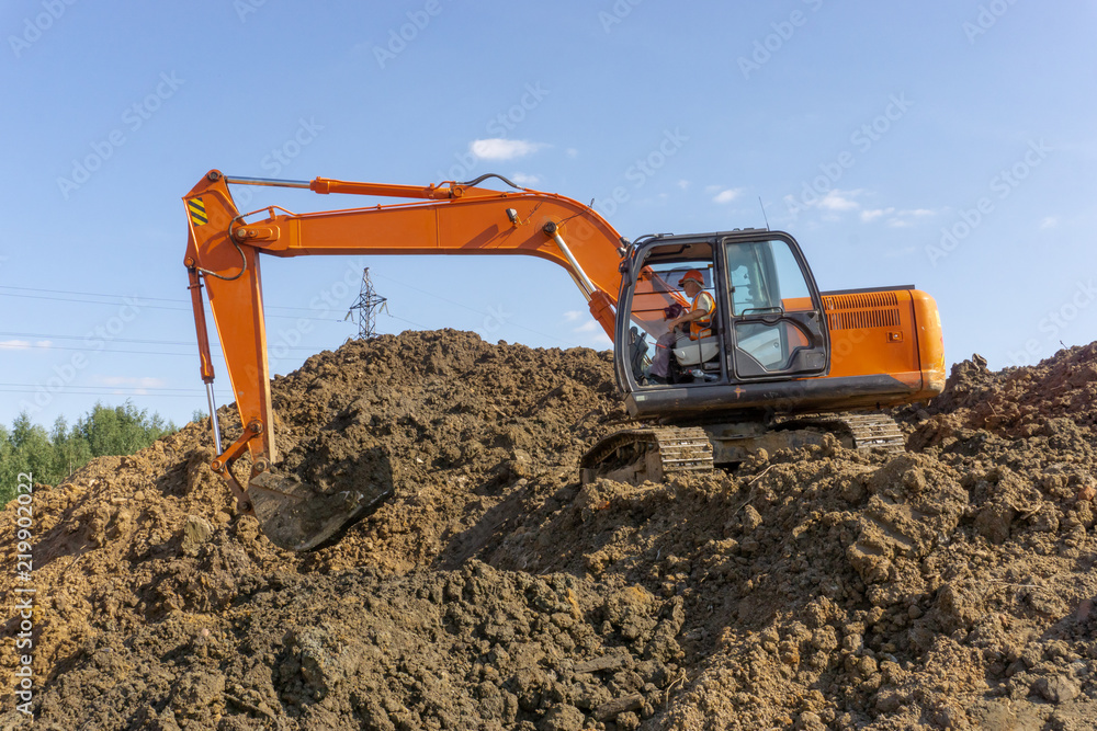 Orange excavator loads the land on a construction site.. Orange excavator loads the land on a construction site..