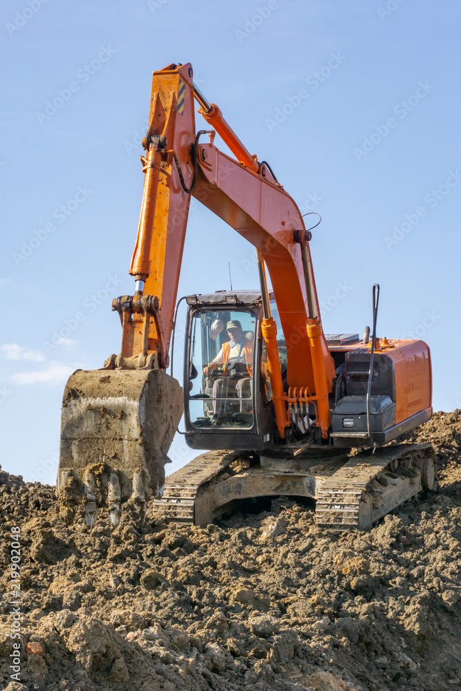Orange excavator loads the land on a construction site.. Orange excavator loads the land on a construction site..