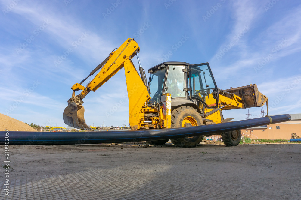 Tractor carries a long pipe for water supply at the construction site