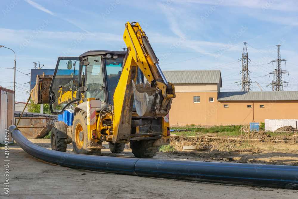 Tractor carries a long pipe for water supply at the construction site Tractor carries a long pipe for water supply at the construction site