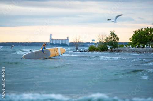Obraz na płótnie Beautiful woman stand up paddle boarding at sunrise or sunset w salonie