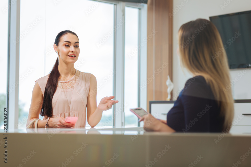 Making an appointment. Joyful pleasant woman talking to the administrator while making an appointment Making an appointment. Joyful pleasant woman talking to the administrator while making an appointment