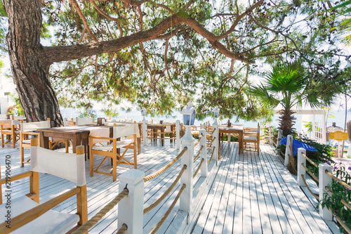 Restaurant with tables on a snow-white terrace overlooking the sea under pine branches. Rest on the sea