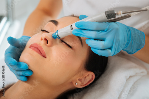 Facial procedure. Delighted nice woman lying on the medical bed with her eyes closed while having hydrafacial