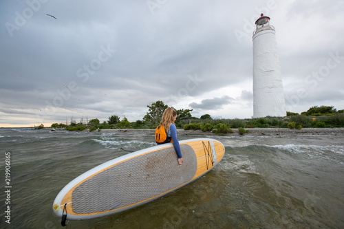 Beautiful woman stand up paddle boarding at sunrise or sunset