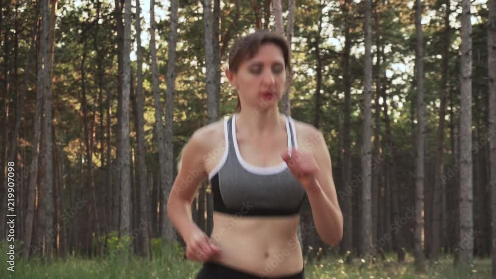 Tired athletic woman running in training in rays of sun Tired athletic woman running in training in rays of sun