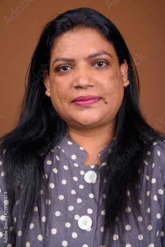 Portrait of mature Indian woman against brown background