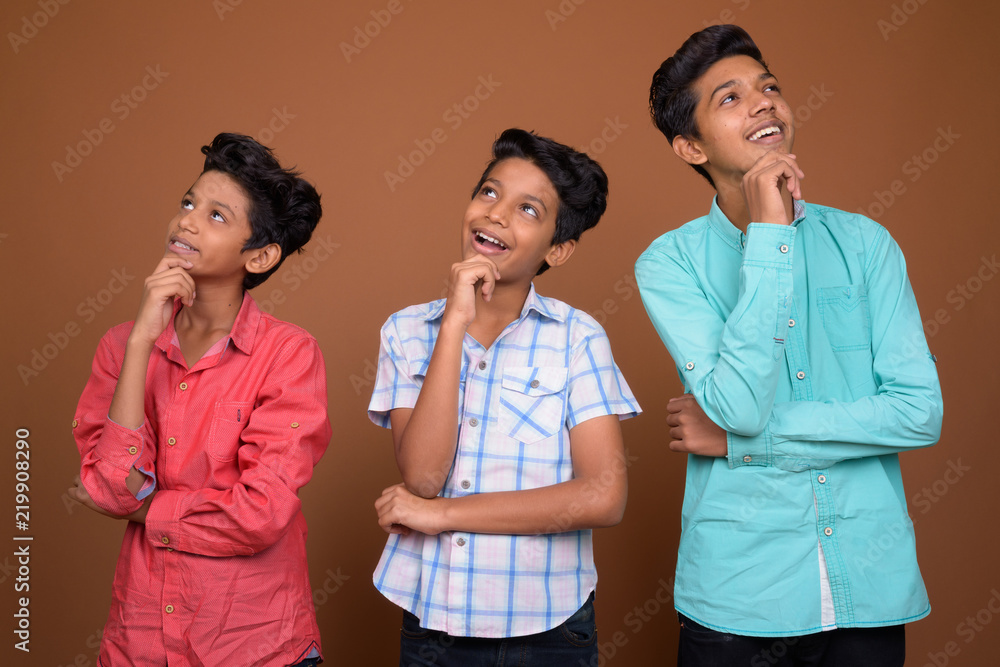 Three young Indian brothers together against brown background Three young Indian brothers together against brown background
