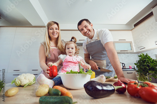 A happy family prepares food from vegetables in the kitchen.