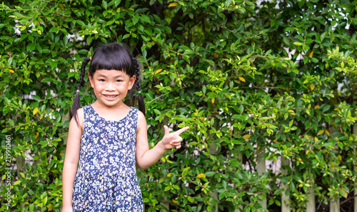 Little girl with big smile standing in front of fence with plant