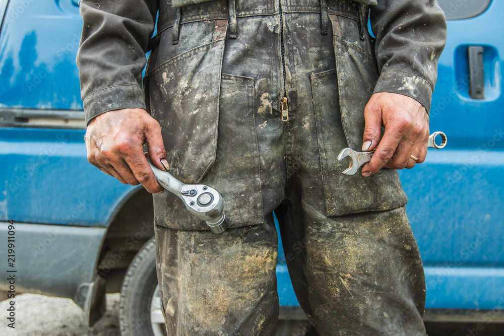 The laborer, who is wearing a dirty overalls and two tools in his hands in  Finland. Stock Photo | Adobe Stock
