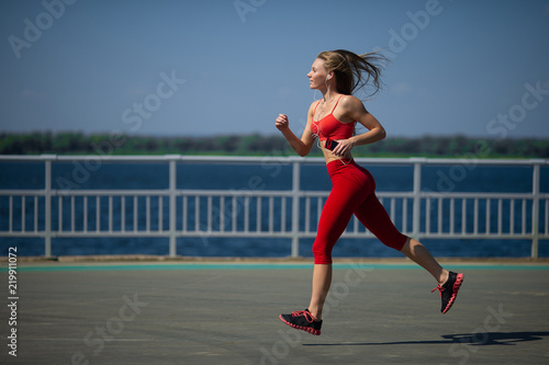 Young fitness woman running on the coast. The concept of a healthy lifestyle © Vladimir