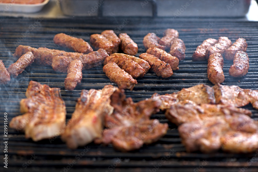 Street food being made in state fair. Traditional meat and sausages grilled in open air market for people. First barbecue party outdoors in spring Street food being made in state fair. Traditional meat and sausages grilled in open air market for people. First barbecue party outdoors in spring