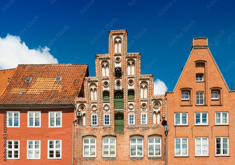 Fototapeta premium Facades of the old historiacal buildings made of red brick. Blue sky on the background. Luneburg, Germany
