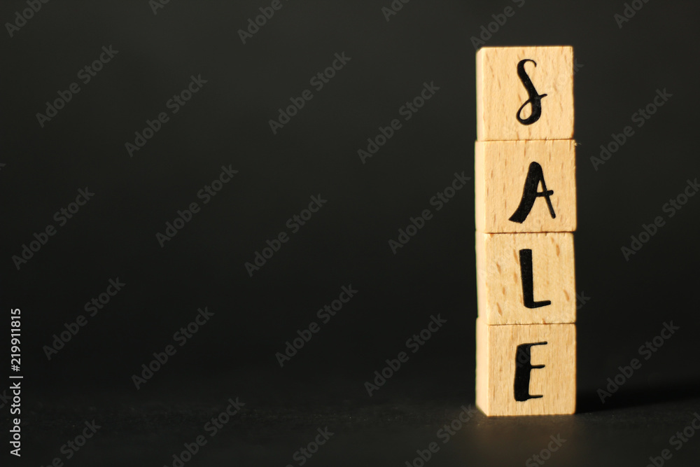 Business Concept: word SALE build from wooden cubes with letters, selective focus, black background, free copy space Business Concept: word SALE build from wooden cubes with letters, selective focus, black background, free copy space