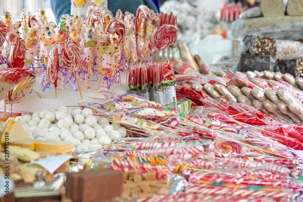 Fototapeta premium Natural honey sourced sweet candy in different shapes and colorful designs at a local state fair. Sweets and lollipops for kids. Concept of unhealthy eating, too much sugar. Diabetes