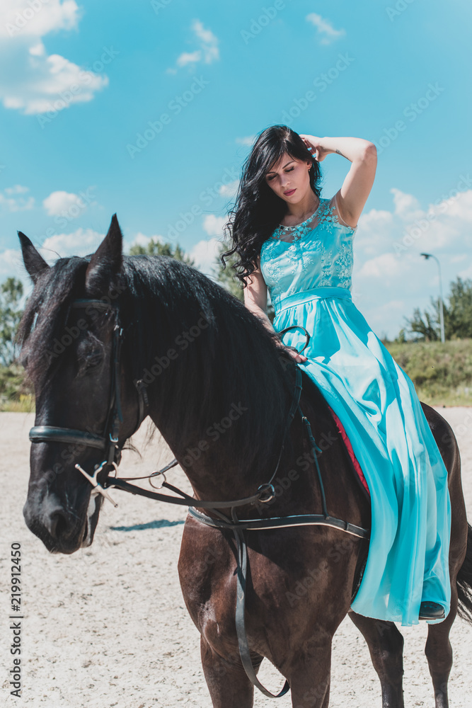 Fototapeta premium Romantic scene woman with a horse in the countryside. Concept of horse and human. Portrait of vintage style artistic woman walking with horse outdoors in turquoise dress