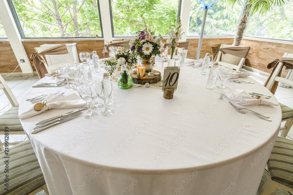 Round wedding table with forest theme, decoration, plates, forks, and glasses.