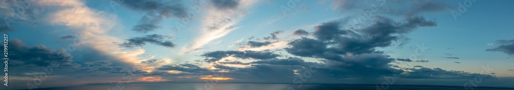 Panorama sky background with clouds during sunset, and the line of horizont.