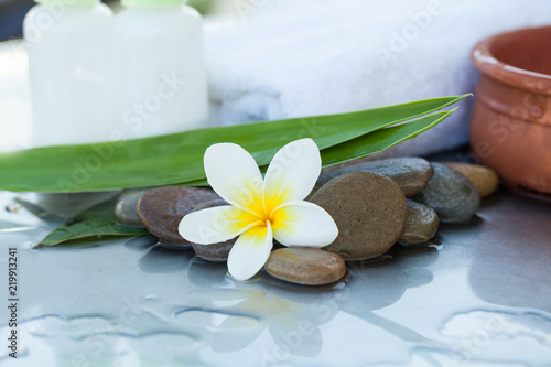 wellness setting with tropical flower  bowl of water  towel and two cream tube for body