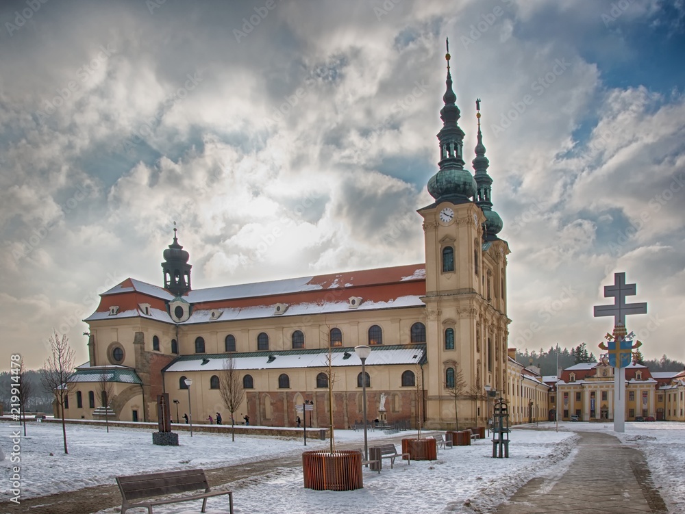 Obraz premium Famous pilgrimage centre Velehrad, Czech Republic during winter and beautiful colors on basilica (church) made by orange sunlight, which works with blue sky as a background