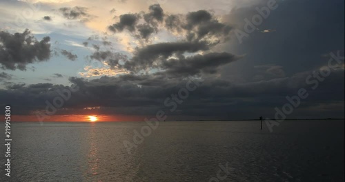 The setting sun emerges from behind ominous storm clouds to cast its rays on central Florida's gulf coast. photo