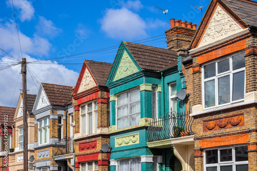 A row of colourful terraced houses in London with overhead cable lines