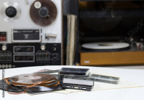 Vinyl record with copy space in front of a collection albums dummy titles. Reel Tape Recorder. Audio cassetes tap.