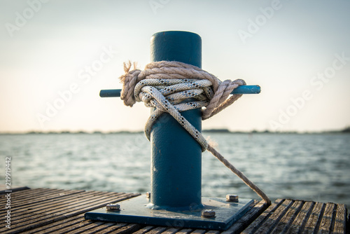 Foto mooring bollard with a rope and a knot in front of water