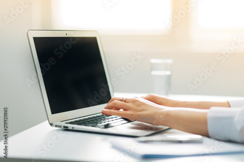 Detail of Woman's Hands typing on laptop with background