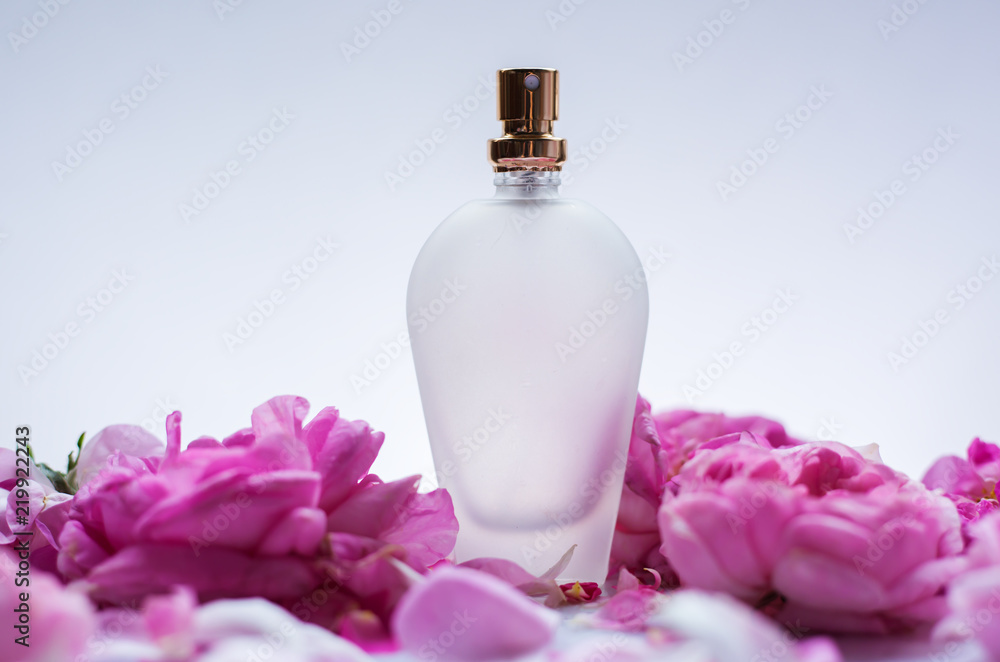Perfume bottle in pink flower roses. Spring background with luxury aroma parfume. Beauty cosmetic fresh aromatic Perfume bottle in pink flower roses. Spring background with luxury aroma parfume. Beauty cosmetic fresh aromatic
