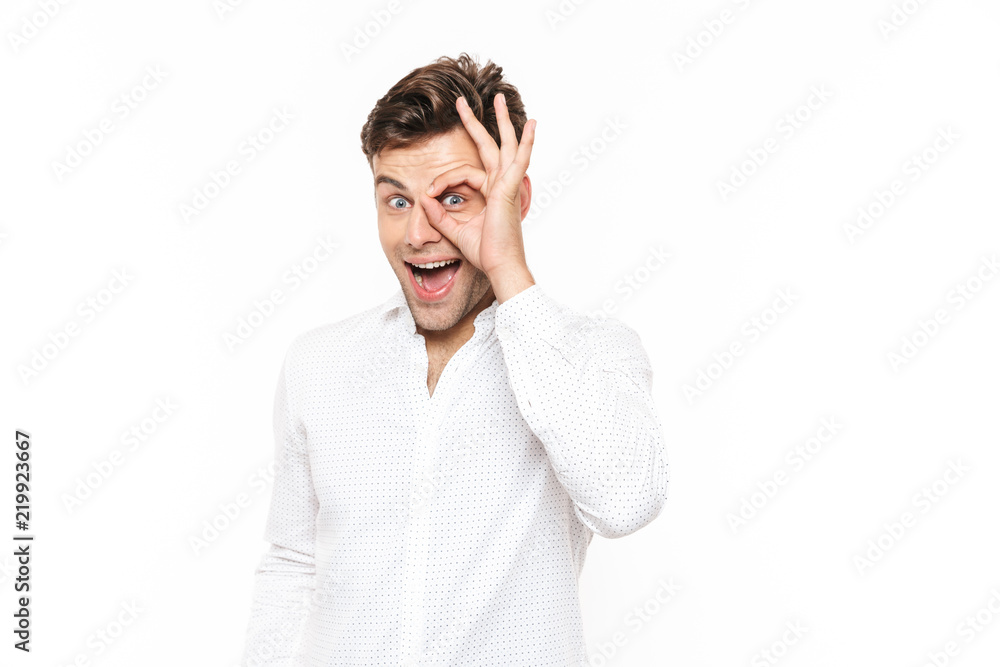 Optimistic man 20s looking at camera through hole or ok sign, isolated over white background Optimistic man 20s looking at camera through hole or ok sign, isolated over white background
