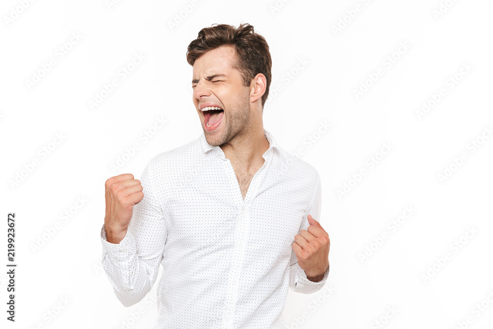Photo of happy man 30s rejoicing and clenching fists, isolated over white background Photo of happy man 30s rejoicing and clenching fists, isolated over white background
