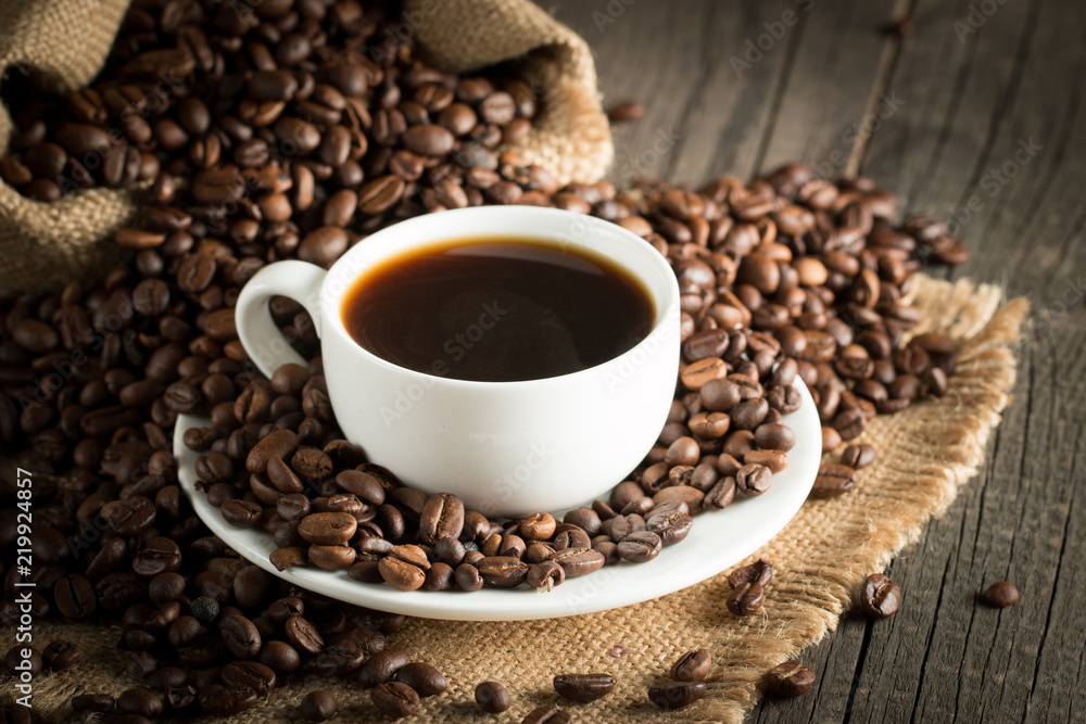 Coffee cup and beans on a rustic background. Coffee Espresso and a piece of cake with a curl. Cup of Coffee and coffee beans on table. Coffee cup and beans on a rustic background. Coffee Espresso and a piece of cake with a curl. Cup of Coffee and coffee beans on table.