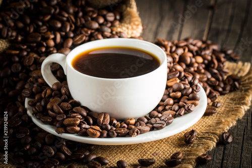 Coffee cup and beans on a rustic background. Coffee Espresso and a piece of cake with a curl. Cup of Coffee and coffee beans on table.