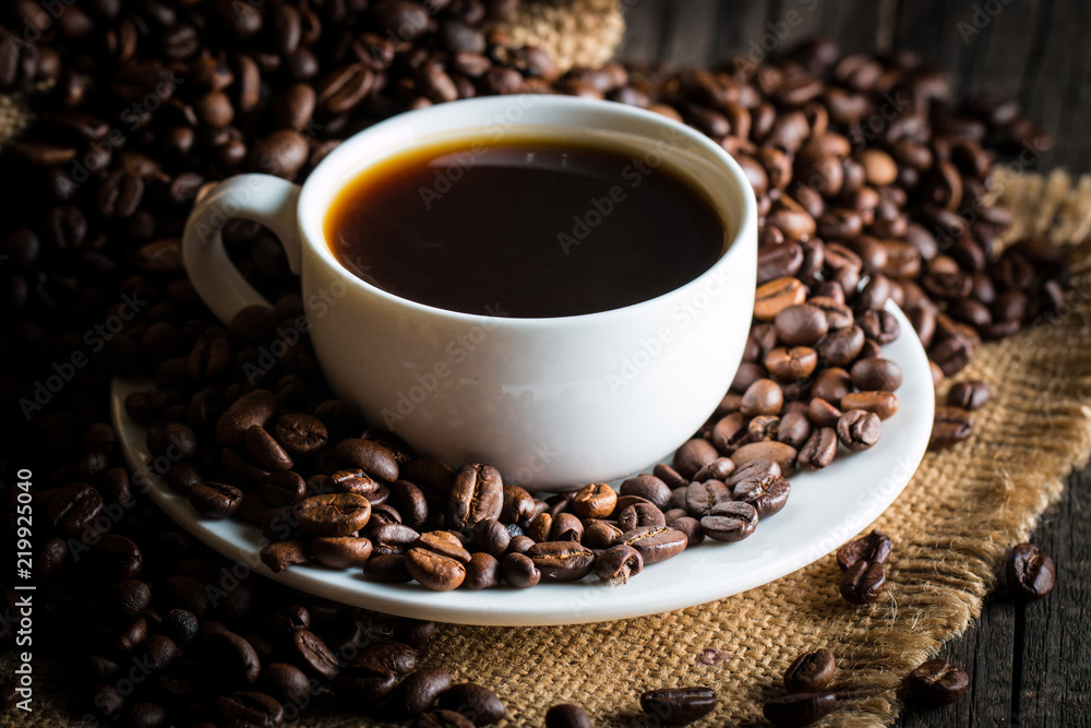 Coffee cup and beans on a rustic background. Coffee Espresso and a piece of cake with a curl. Cup of Coffee and coffee beans on table. Coffee cup and beans on a rustic background. Coffee Espresso and a piece of cake with a curl. Cup of Coffee and coffee beans on table.