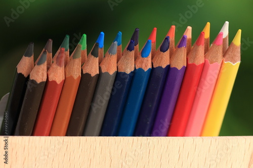 Colored pencils with a basket of knowledge on the grass