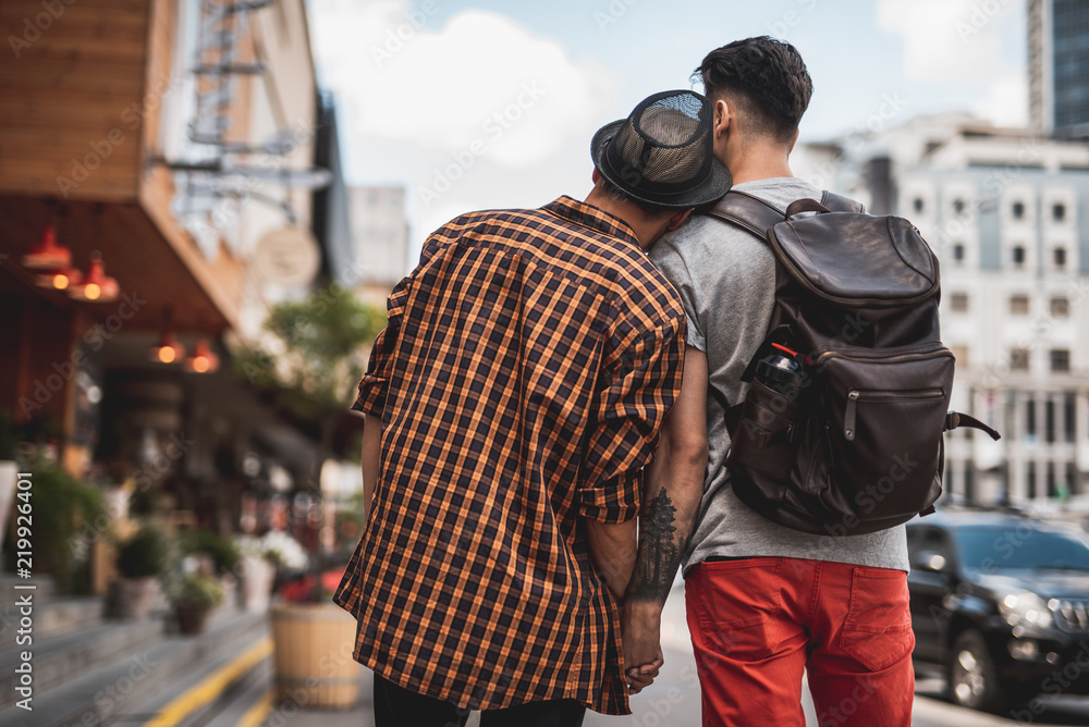 Man putting head on shoulder of another dude while holding hand of comrade on street. They turning back to camera Man putting head on shoulder of another dude while holding hand of comrade on street. They turning back to camera
