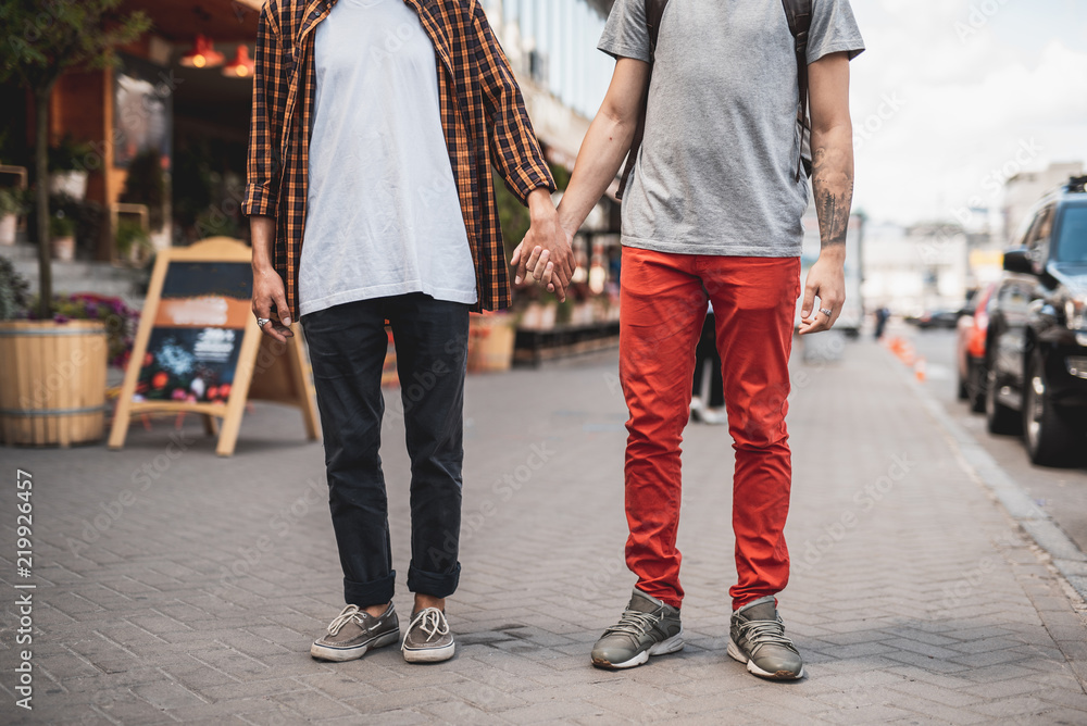 Man holding hand of friend while standing on sidewalk on street. Comrades spending time together concept Man holding hand of friend while standing on sidewalk on street. Comrades spending time together concept