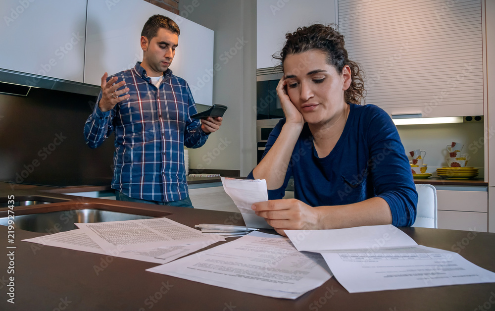 Fototapeta premium Desperate young couple with many debts reviewing their bills. Financial family problems concept.