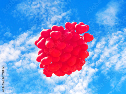 Scarlet heart shaped balloons against the blue sky. Soft focus processing. Symbols of love, romance and day of Saint Valentines , conceptual background. Red balls in the shape of heart