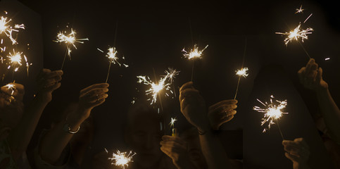dark night celebrate concept with lot of hands taking and using light sparkles fire together. have fun for new year eve or party. companionship and friendship during celebration. happy lifestyle