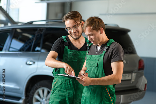 Two young guys in green overalls work at a car service © Oleksandr