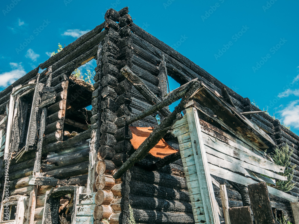 Burned wooden house after fire, ruined building, disaster or war aftermath
