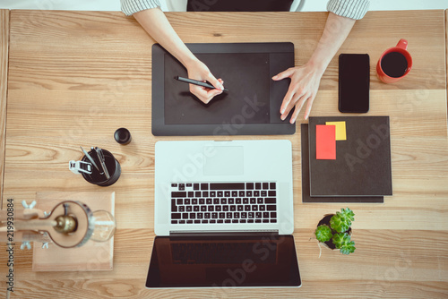 cropped shot of woman working with drawing tablet and laptop on tabletop photo